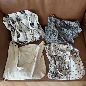 Set of four large linen tote bags with ethnic paisley patterns on a leather background