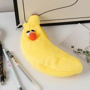 Close-up of a plush banana-shaped pencil case with a metal hook on a white desk