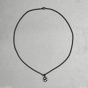 Detail of creative black and white football soccer pendant on fine metallic chain
