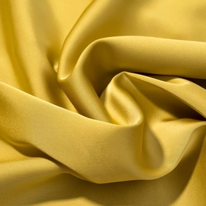 Macro shot of yellow satin fabric showing luxurious smooth texture and elegant drape