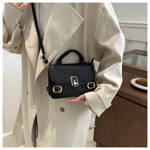 Detailed shot of black crocodile embossed small square bag with gold metal buckle