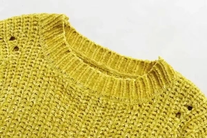 Close-up of yellow chenille knit sweater featuring a ribbed crew neck and openwork detail