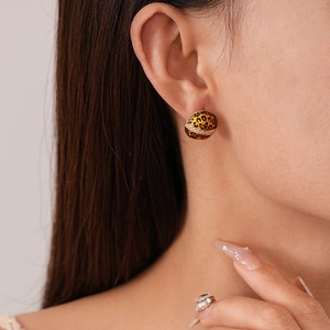 Close-up of leopard print dome earrings with crystal inlay shown on a model