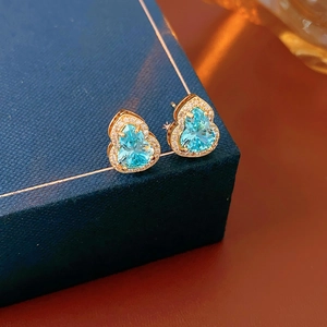 Detail of heart-shaped blue gemstone stud earrings on a luxury velvet jewelry box