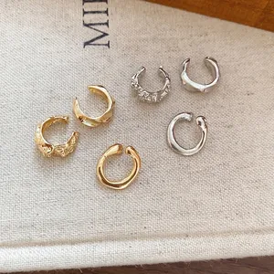 Ensemble de boucles d'oreilles rondes irrégulières en métal doré et argenté sur lin