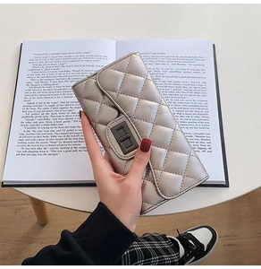Detail of champagne gold quilted wallet with metal twist lock held over an open book