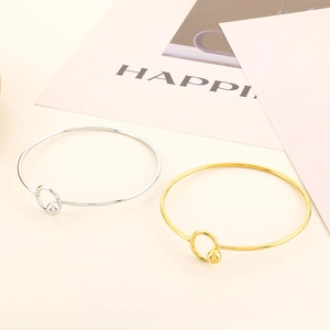 Detail of minimalist gold and silver open bangles with elegant beads on a warm beige background