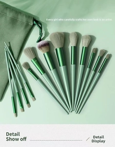 Macro view of 13 green makeup brushes with soft gray bristles and velvet pouch