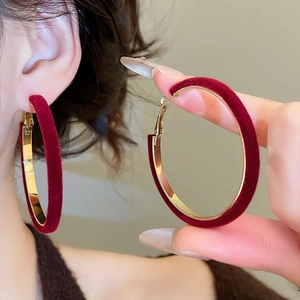 Close-up of red velvet and gold metal geometric hoop earrings on female model