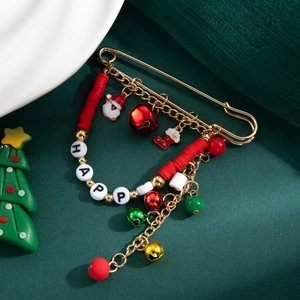 Détail d'une broche de Noël avec cloches dorées et charms Père Noël sur fond vert