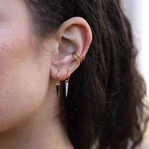 Close-up of gold ear cuff set with spike pendants and cubic zirconia on model