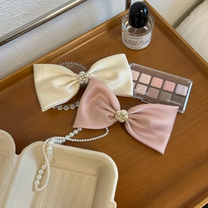 Oversized satin bow hair clips in beige and pink with pearl flower accents