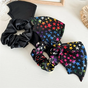 Close-up of black satin scrunchies with bat wings and colorful star patterns