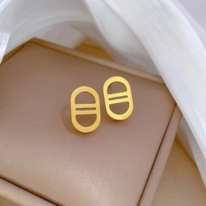 Macro detail of gold anchor link stud earrings on luxury jewelry box with soft light