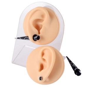 Detail of black piercing taper and silver tunnel shown on silicone ear models
