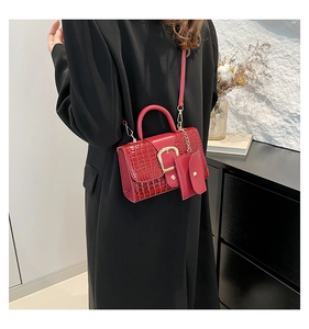 Detail of red crocodile pattern handbag featuring a mini detachable pouch and gold clasp