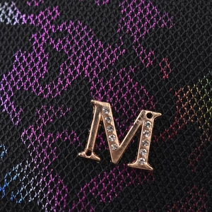 Macro detail of metallic M-logo with rhinestones on colorful iridescent mesh fabric