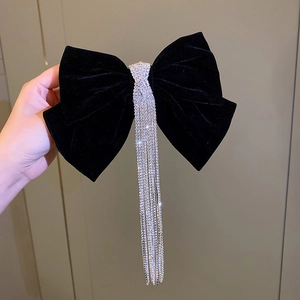 Close-up of black velvet bow hair clip with long sparkling rhinestone tassel details