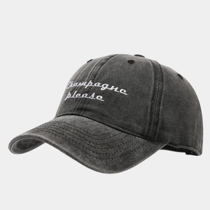 Detail of washed dark grey baseball cap featuring white Champagne Please embroidery