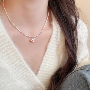 Gros plan d'un collier de perles avec un pendentif poney rose sur un mannequin