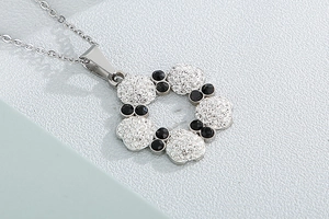 Detailed close-up of a silver-tone five-petal flower pendant with crystals and black stones