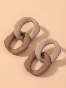 Detail of interlocking beige and brown matte acrylic chain link earrings on pink background
