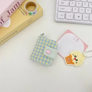 Detailed view of mini plaid fabric pouch with heart button and green snap closure