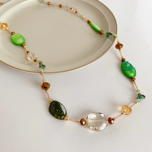 Macro detail of bohemian beaded long necklace with green glass and agate stones