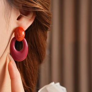 Close-up of vintage oval cutout earrings in red and purple resin worn by a model