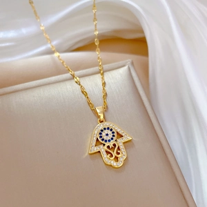 Golden Hamsa Hand and Evil Eye necklace with crystals on silk background