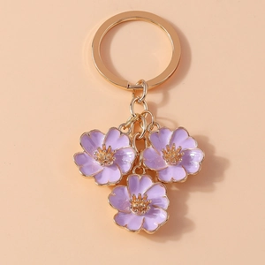 Close-up of purple peach blossom charms on a gold alloy keychain with floral details