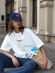 Dettaglio della t-shirt in cotone bianco con stampa ASSERTIVE in un contesto street