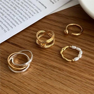 Close-up of assorted 925 sterling silver rings with irregular pearls on a wooden desk