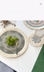 Detail of woven boho placemat with mandala pattern, fringe edges and glass plate