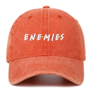 Detailed embroidery of white ENEMIES text on a rustic orange washed cotton baseball cap