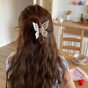 Blue butterfly hair claw clip with pink heart patterns shown in a lifestyle setting