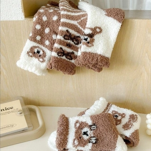 Plush bear coral fleece thermal socks for winter displayed on a wooden shelf