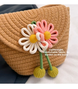 Detailed close-up of a straw bucket bag with handmade knit flower charms and beige strap