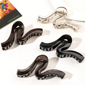 Detail view of four glossy S-shaped large hair claw clips in transparent and solid colors
