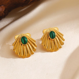 Golden shell earrings with green malachite stone on silk fabric background