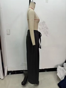 Detail view of high-waisted black wide-leg trousers with an adjustable waist tie belt