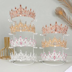 Golden metal bridal crown display stands featuring rhinestone tiaras in various colors