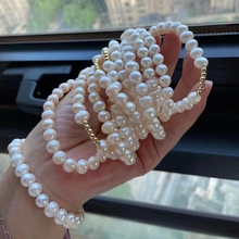 Detail of natural freshwater pearl bracelets with gold beads on a hand display