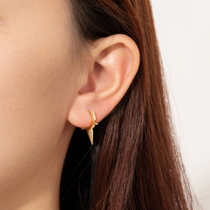 Close-up of gold S925 silver hoop earrings with diamond-set spikes on a female model