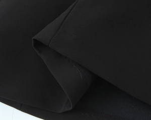 Gros plan détaillé de la texture du tissu noir et des coutures surjetées de la robe