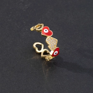 Detailed close-up of gold heart ring with red enamel evil eye and zircon stones