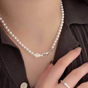 Close-up of elegant 925 silver pearl necklace and minimalist ring on a female model