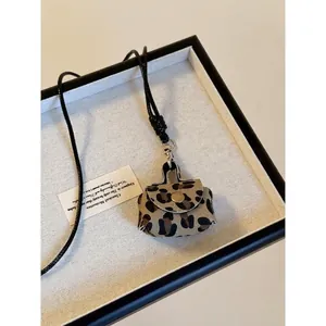 Dettaglio mini borsa leopardata con cordino intrecciato nero e chiusura in metallo