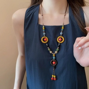 Detailed close-up of a handmade ethnic ceramic bead necklace on a blue sleeveless top