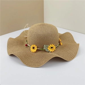 Detail of woven straw sun hat featuring a wavy brim with sunflower and green leaf accents